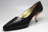 Side veiw of black snake skin shoes featuring gold coma heels  and a gold leather interior 