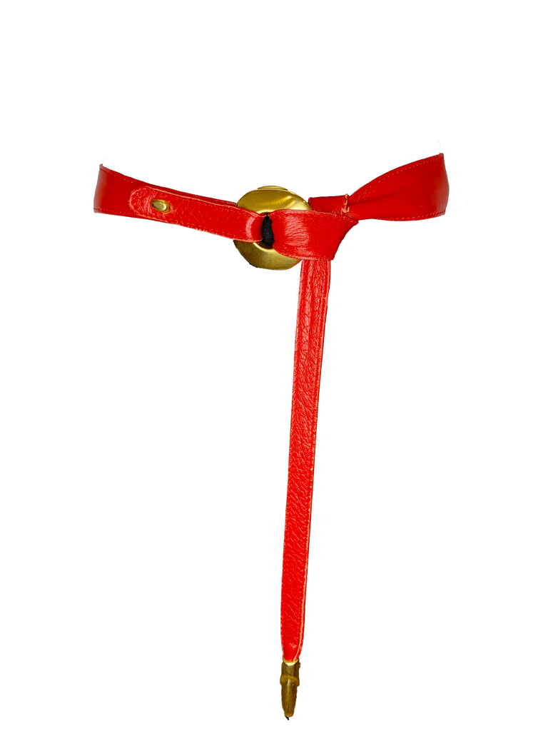 Red leather belt with round gold metal buckle that belt loops through to close. Gold  metal tip on end of belt