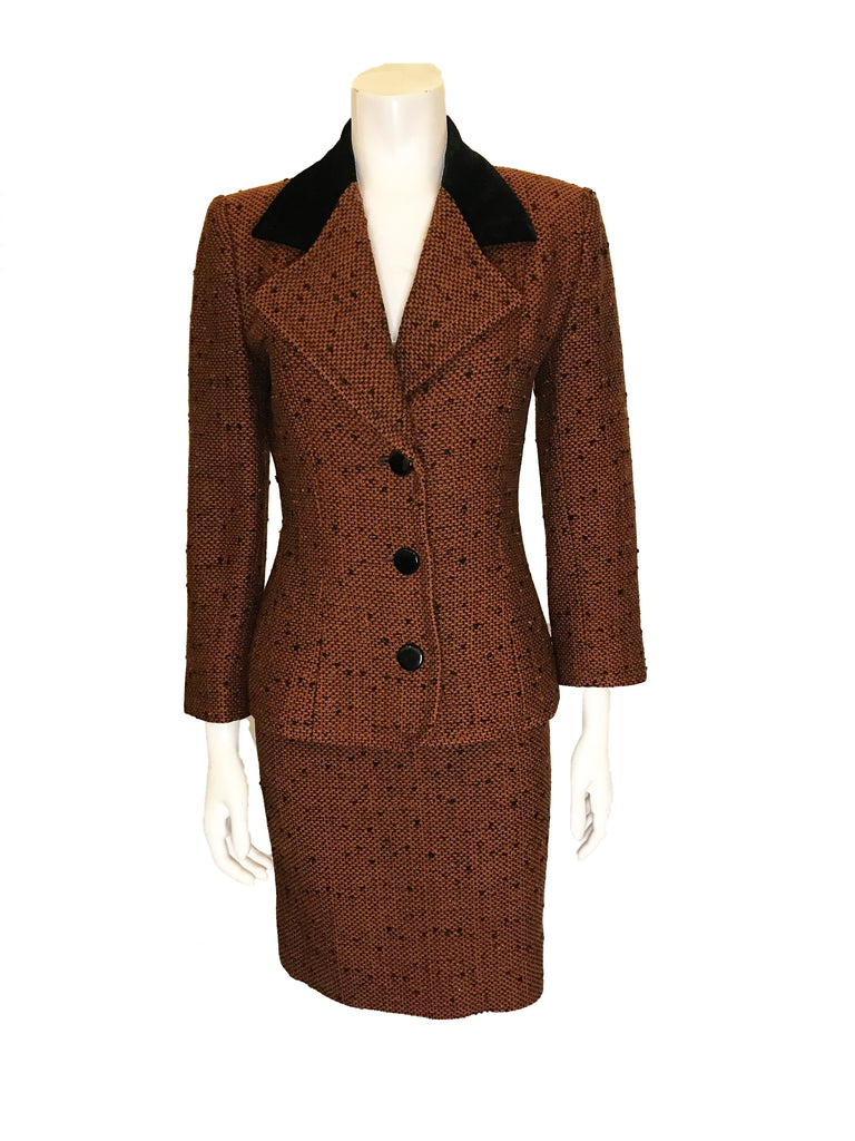 Front view on mannequin Two piece suit with skirt in burnt orange tweed wool with metallic thread. Jacket is hip length with three quarter sleeves and three button closure. Skirt is straight and knee length   