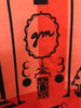 Closeup of GM logo on a coral and black scarf by Gene Meyer
