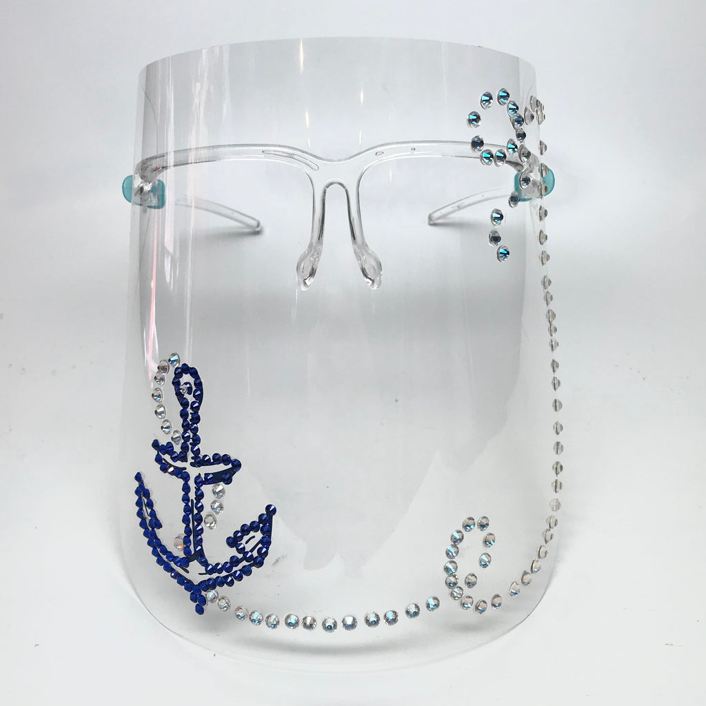 A Face shield featuring a printed anchor outlined in blue Swarovski crystals and a  winding "chain" of Swarovski crystals running across the bottom of the mask up to the temple