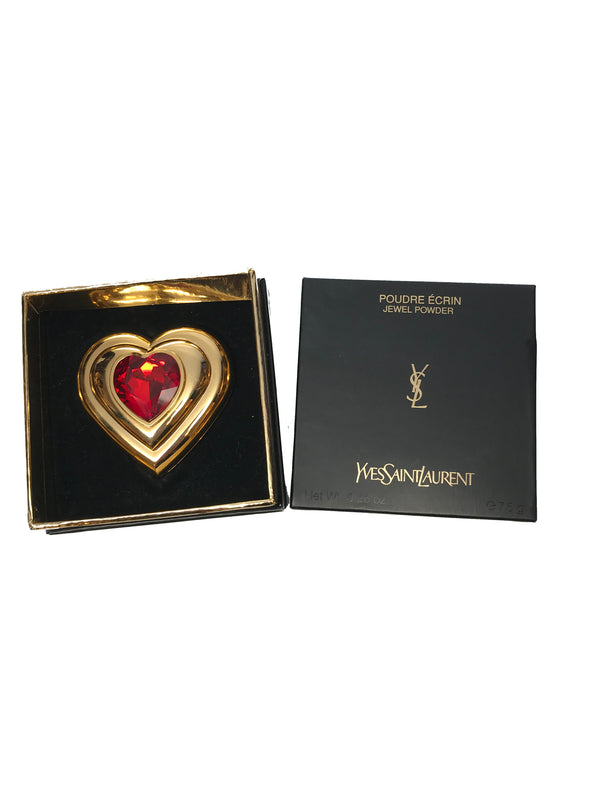 Front view of Yves Saint Laurent gold Heart shaped makeup compact with large red jewel placed in its original packaging.