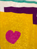 Closeup of Charles Jourdan silk colorblock scarf in sea foam green, off white, and marigold with a hot pink heart