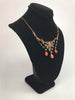 Side view of Victorian era necklace featuring seed pearls and polished coral beads draped on a Black velvet jewelry display neck