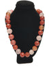 Front view of necklace display wearing a necklace of faceted round beads in varying shades of rose and orange