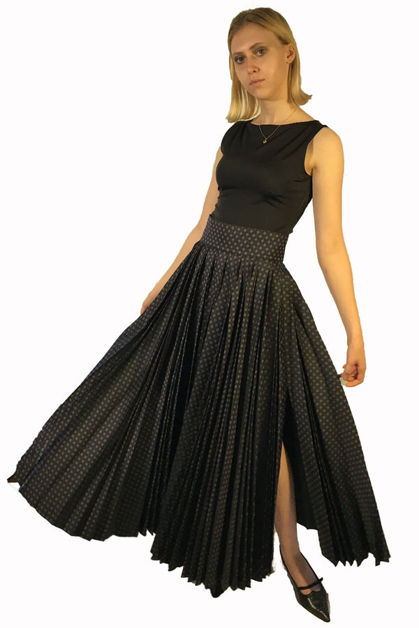 Long, high waisted full pleated skirt with side slit. Pattern is navy blue with green and white accents. 