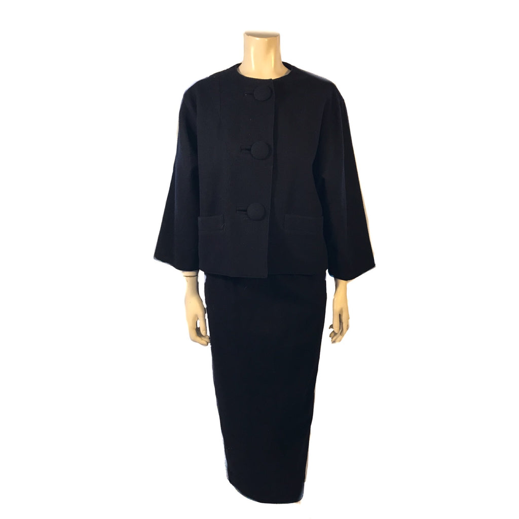 Navy, wool, two-piece skirt suit. Jacket is boxy and hip length with three buttons. Skirt is straight and midcalf length 