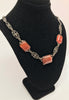 Diagonal front view of necklace display with a necklace featuring a decorative sterling silver and marcasite chain with three rectangular carnelian stones