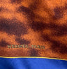 Small square silk pocket scarf with a blue border, mottled brown center pattern and the word BELAMI on the right bottom corner.