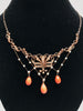 Front view close up of Victorian era necklace featuring seed pearls and polished coral beads draped on a black velvet jewelry display neck