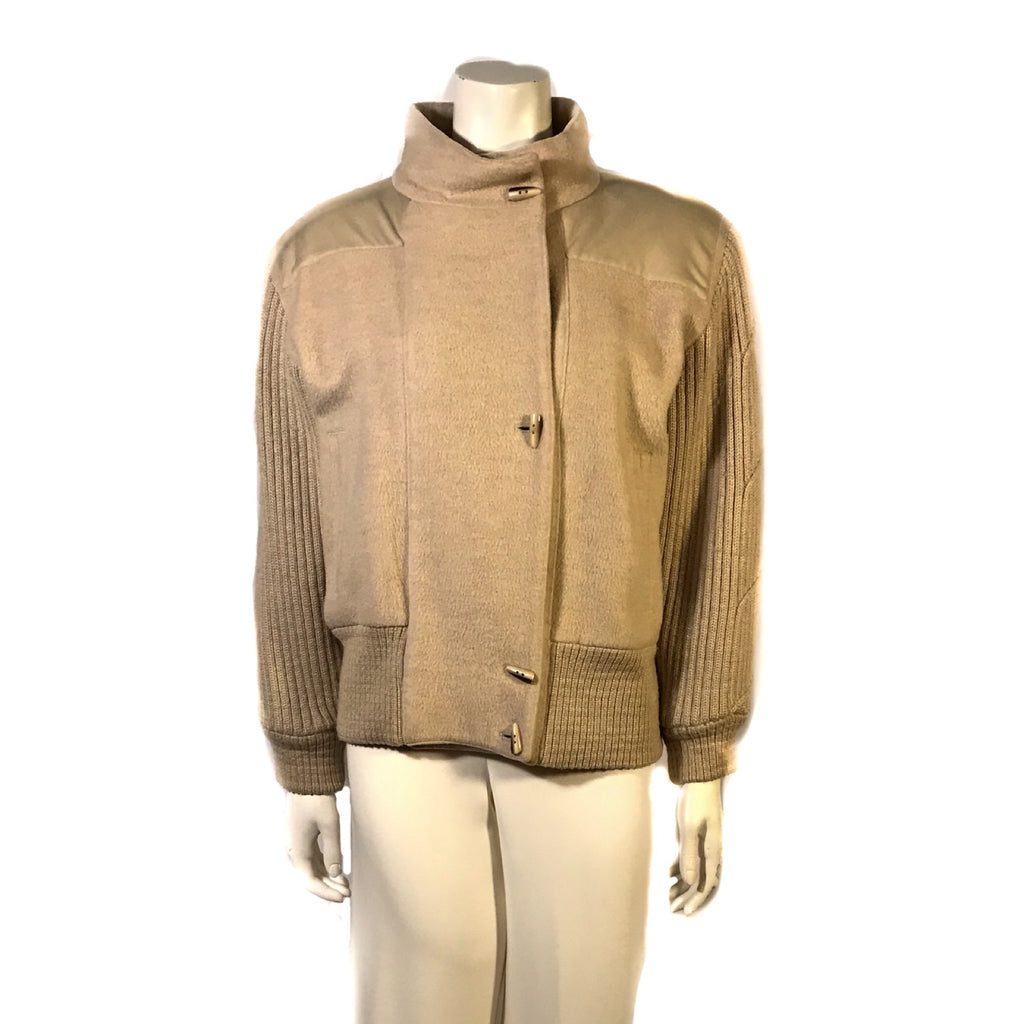 Front  view on mannequin beige wool waist length jacket with knitted wool sleeves and banded bottom. Four front buttons 
