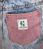 Blue, knee-length, high-waist, acid-wash skirt with front-zipper and button at waist. Two back pockets in pink and green. Naf Naf patch on red pocket. 