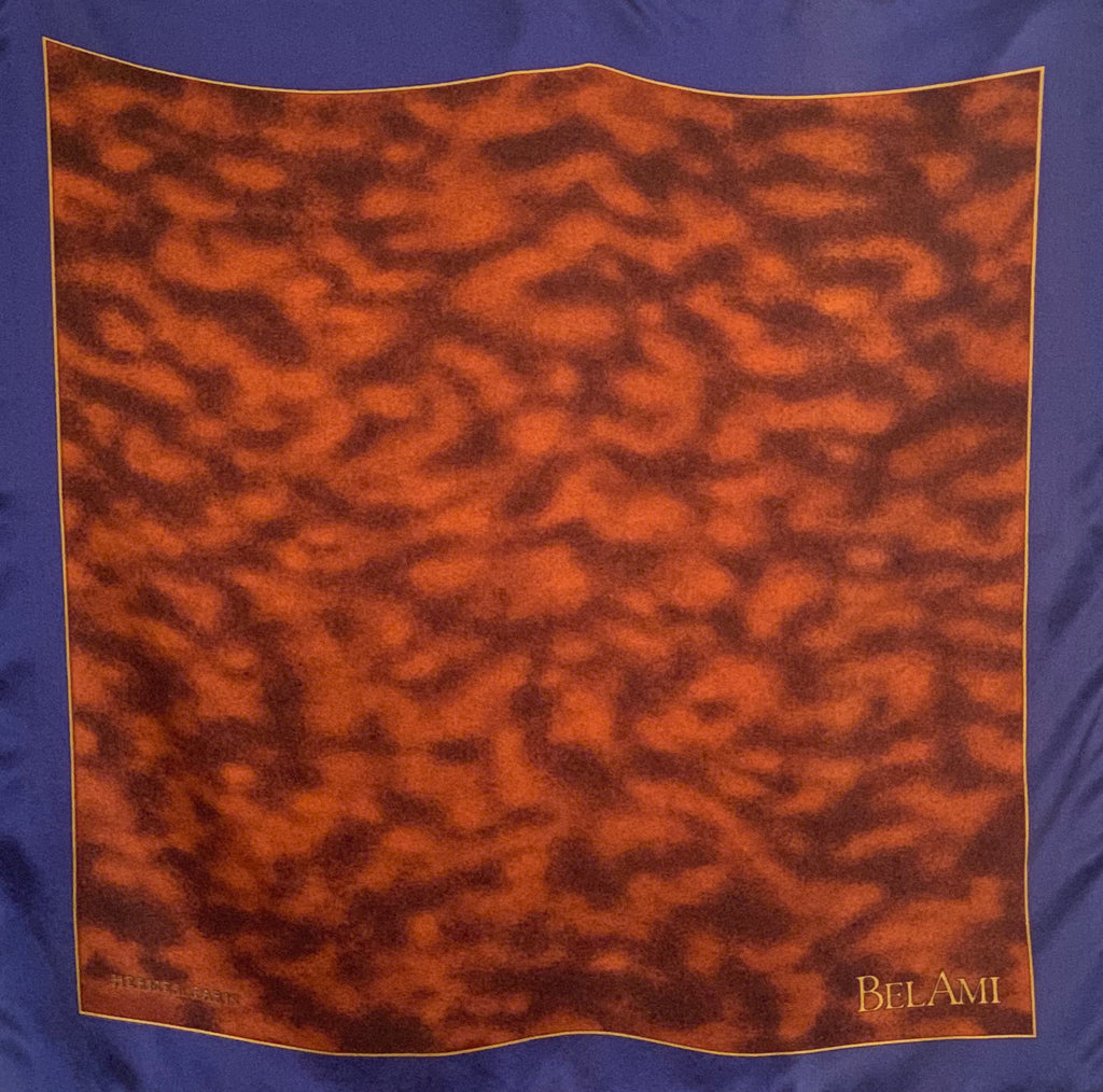Small square silk pocket scarf  with a blue border, mottled brown center pattern and the word BELAMI on the right bottom corner. 