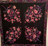Black silk square scarf with four floral patterns in pink, purple, blue. and white. Border is a paisley pattern in a matching color scheme.