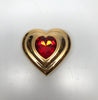 Front view of Yves Saint Laurent gold Heart shaped makeup compact with large red jewel in center without included packaging. 