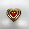 Front view of Yves Saint Laurent gold Heart shaped makeup compact with large red jewel in center without included packaging.