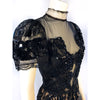 Short sleeve evening dress covered in lace and black beading. The front has a sheer insert. Skirt is knee length.