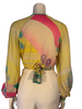 Yellow, long-sleeve, wrap top with a hot pink, turquoise, and purple floral print. 