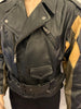 Black, zip-up leather jacket with diamond-shaped patchwork sleeves in black, brown, and tan and a black belt. 