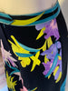 Black, high-waisted, wide-leg pants with a lime green, purple, aqua, and pink flower print. 
