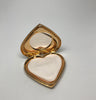 View of open Yves Saint Laurent makeup compact revealing small round mirror and heart shaped powder applicator.