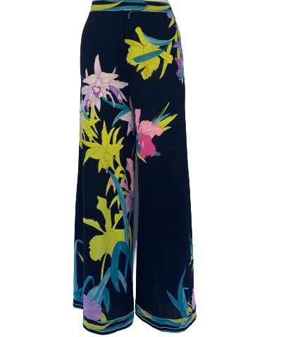 Black, high-waisted, wide-leg pants with a lime green, purple, aqua, and pink flower print. 