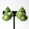 Close up front view of green sculptural shell shaped earrings dotted with faux pearl accents. 