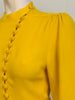 Marigold 2-piece set. High-neck, long-sleeve, asymmetrical, button-up jacket with slight peplum. High-waisted, wide-leg pants.