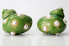 Front view of green sculptural shell shaped earrings dotted with faux pearl accents.