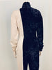 Back view of mannequin wearing a Norma Kamali half black velvet, half white jersey jumpsuit with a center zipper. 