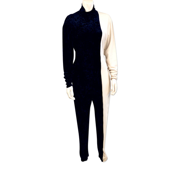Full length view of mannequin wearing a half black velvet, half white jersey jumpsuit by Norma Kamali. 